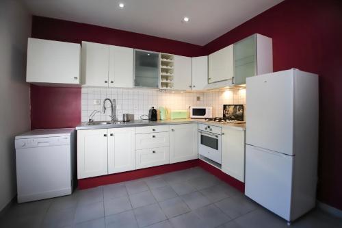 - une cuisine avec des appareils électroménagers blancs et des murs rouges dans l'établissement Maison tendance avec jardin, centre village, Alpilles, familles, à Eyragues