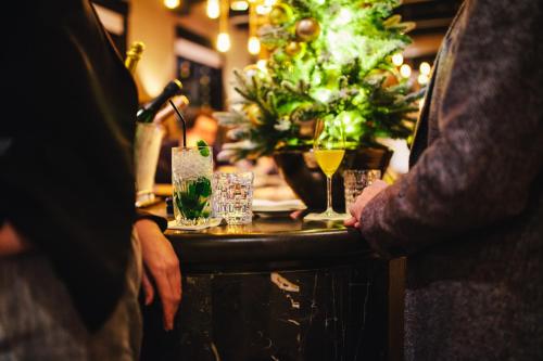 a group of people standing at a bar with drinks at The Dylan Amsterdam - The Leading Hotels of the World in Amsterdam