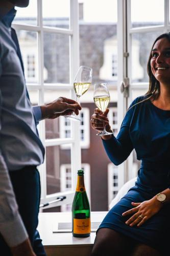 a woman holding two glasses of wine next to a bottle at The Dylan Amsterdam - The Leading Hotels of the World in Amsterdam