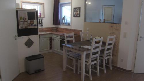 eine Küche mit einem Tisch und Stühlen sowie einem Kühlschrank in der Unterkunft Ferienwohnung Apfelbaum in Schonungen