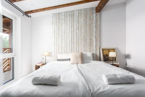 a white bedroom with a large white bed with two pillows at Къщи за гости Сноуфлейк Snowflake Chalet and Snowflake Lodge in Bansko