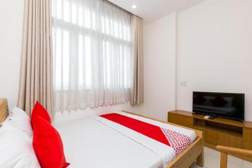 a bedroom with a bed with red pillows and a television at Ph&uacute; Ho&agrave;ng Nam Hotel in Ho Chi Minh City