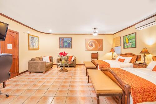 a hotel room with two beds and a living room at Hotel Casa Roland San Jose in San José
