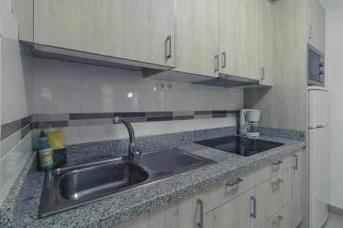 a kitchen with a stainless steel sink and a refrigerator at Puerto Mogan Apartment in Puerto de Mogán