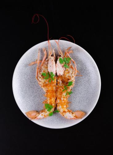 a plate of food with shrimp on a black background at Vox Hotel in Jönköping