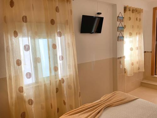 a bathroom with a shower curtain and a television at Duarte Houses - Casa T1 - com vista mar in Nazaré