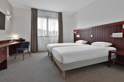 a hotel room with two beds and a desk at KYRIAD Périgueux - Boulazac in Saint-Laurent-sur-Manoire