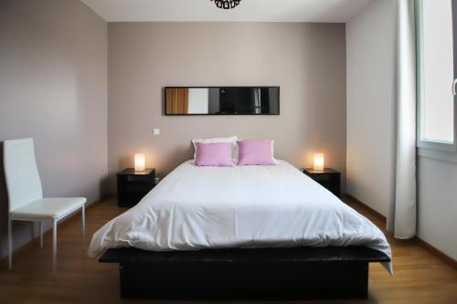a bedroom with a large bed with two pink pillows at Maison tendance avec jardin, centre village, Alpilles, familles in Eyragues
