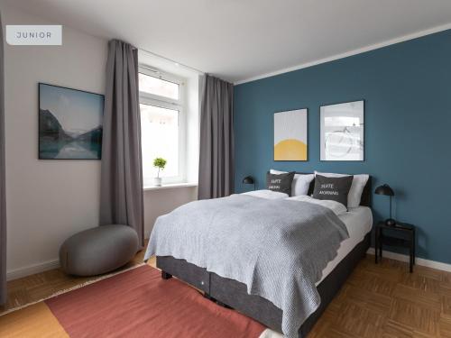 Schlafzimmer mit einem Bett mit blauen Wänden und einem Fenster in der Unterkunft Apartments Berlin Aroser Allee in Berlin