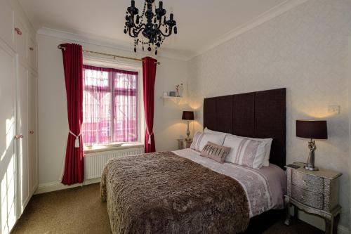 a bedroom with a bed with red curtains and a chandelier at Robertsbrook Guest House in Swanage