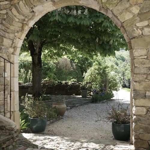 une voûte dans un jardin avec des plantes en pot dans l'établissement La Cour du Marronnier, à Pont-de-Barret