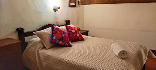 a bedroom with a bed with two pillows on it at Posada Portal de la Villa in Villa de Leyva