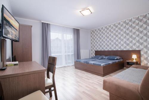 Habitación de hotel con cama, escritorio y TV. en Super Pokoje Tom, en Władysławowo