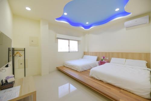 een slaapkamer met 2 bedden en een blauw plafond bij 小日子民宿 in Magong