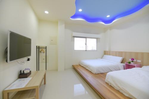 een slaapkamer met 2 bedden en een blauw plafond bij 小日子民宿 in Magong