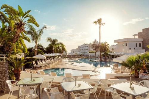 普羅塔拉斯的住宿－拉塔尼亞花園公寓式酒店，一个带游泳池和桌椅的度假酒店