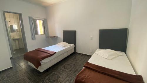a bedroom with two beds and a bathroom at Hotel dos Nobres in Poços de Caldas
