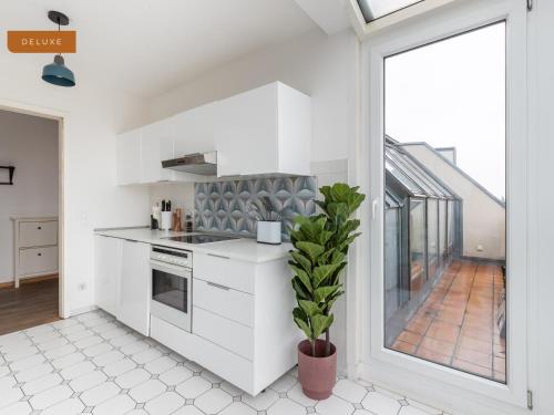 eine Küche mit weißen Schränken und einem großen Fenster in der Unterkunft Apartment Berlin Am Friedrichshain in Berlin