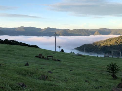 a grassy hill with a view of a fog covered valley at Cabana Monte - Pousada Colina dos Ventos in Urubici