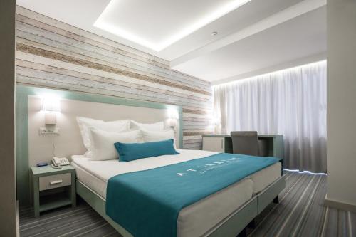 a bedroom with a large bed with a blue blanket at Atlantic Garden Resort in Odesa
