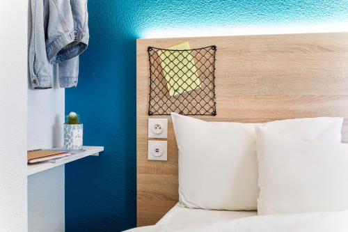 a bedroom with blue walls and a bed with white pillows at hotelF1 La Rochelle Angoulins "Rénové" in Angoulins