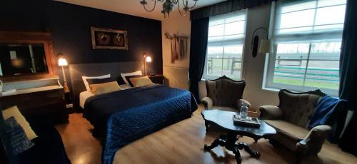 a bedroom with a bed and a couch and a table at Bed & Breakfast de Kienstee in Schoondijke