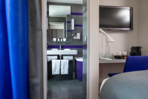a hotel room with a bathroom with a sink and a tv at Le Pradey in Paris