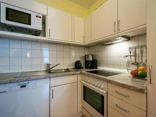 eine Küche mit weißen Schränken, einer Spüle und einer Mikrowelle in der Unterkunft Kaiservillen Heringsdorf - 1-Raum-Ferienwohnung mit Balkon D113 in Heringsdorf