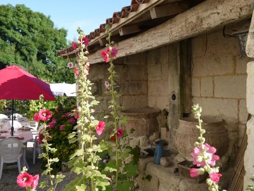 a garden with pink flowers next to a building at Chambres d'Hôtes - Les Bujours in Saint-Georges-des-Côteaux