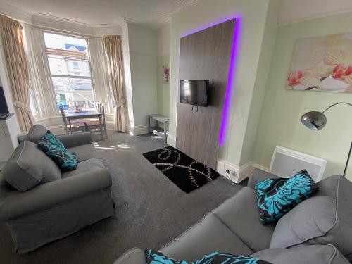 una sala de estar con 2 sofás y una luz púrpura en Oceana Holiday Apartments en Bridlington