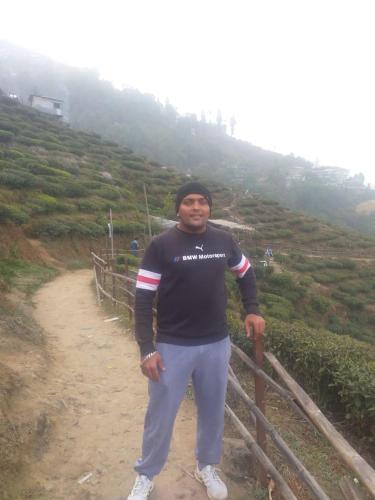a man standing next to a fence on a hill at Madys view -Aaple Ghar in Darjeeling