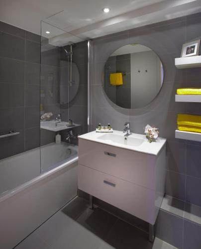 une salle de bain avec un lavabo, un miroir et une baignoire dans l'établissement Citadines Place d'Italie Paris, à Paris