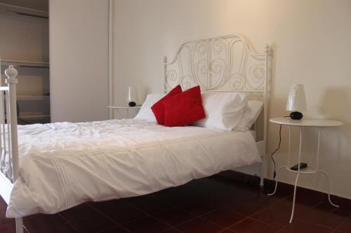 a bedroom with a white bed with a red pillow at Alveiros Apartamentos Praia dos Aveiros in Albufeira