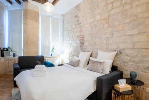 - une chambre avec un grand lit blanc et un mur en briques dans l'établissement GemBnB Luxury Apartments - Residence Timbaud Paris-Oberkampf, à Paris