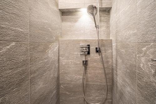 La salle de bains est pourvue d'une douche avec un pommeau de douche. dans l'établissement LAAX Homes - Val Signina 7-12, à Laax