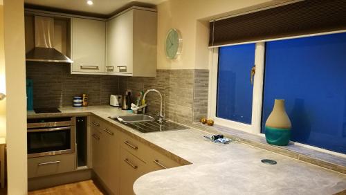 uma cozinha com um lavatório e uma grande janela em Lowghyll suite em Bowness-on-Windermere