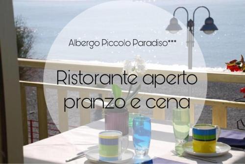 a table with plates and glasses on a balcony at Hotel Piccolo Paradiso in Bordighera
