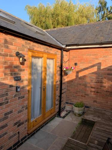 a brick house with a wooden door on it at The Forge Guest Rooms in Long Whatton