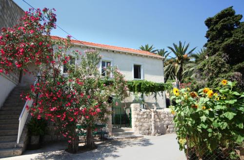 a white house with flowers in front of it at Guest House Katica in Zaton