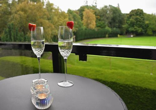 two wine glasses on a table with a view of a golf course at Gleneagles Luxury Apartments in Auchterarder