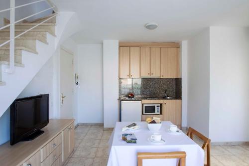 a kitchen with a white table and a tv at Apartamentos La Torreta in Altafulla