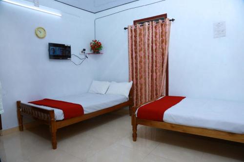 a bedroom with two beds and a tv in it at Olivia Homestay Idukki in Idukki