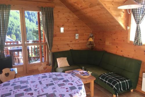 a living room with a green couch and a table at Le Cubèt Hameau des Chazals Nevache Hautes Alpes in Névache