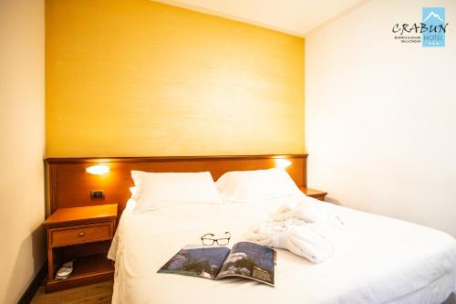 a bed with a book and a teddy bear on it at Crabun Hotel in Pont-Saint-Martin