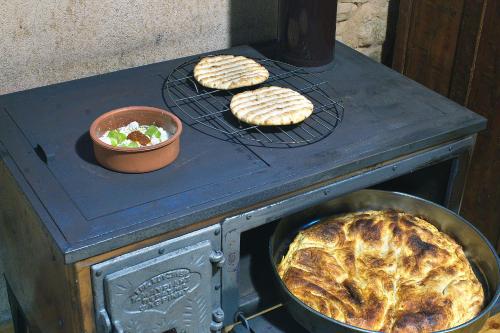 a stove with two pies and a bowl of salad at Lithia s Stonehouse. Το πέτρινο στη Λιθιά - Καστοριά in Lithiá