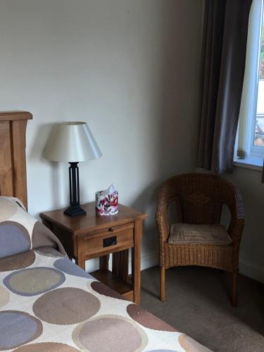 a bedroom with a bed and a chair and a lamp at Chauffeurs Cottage at The Stoep in Paignton