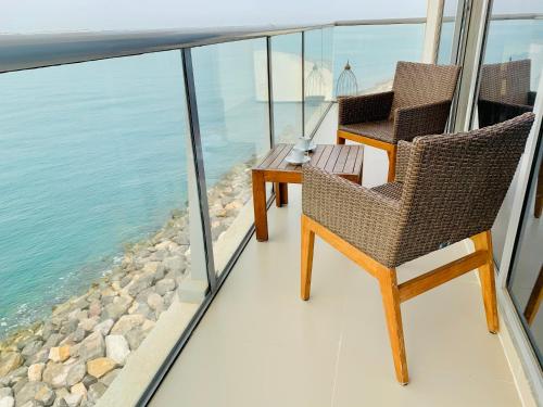 two chairs and a table on a balcony overlooking the water at Luxurious 2 bedroom Beachfront Apartment - direct seaview in Ras al Khaimah