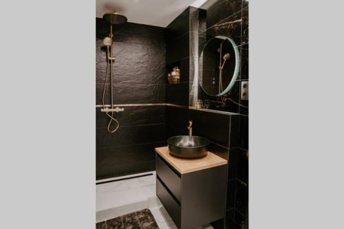 a black bathroom with a sink and a mirror at APARTMENT A&D Downtown in Poprad