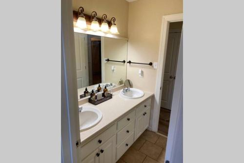 ein Badezimmer mit zwei Waschbecken und einem großen Spiegel in der Unterkunft The Crimson - Game Day Rental in Tuscaloosa