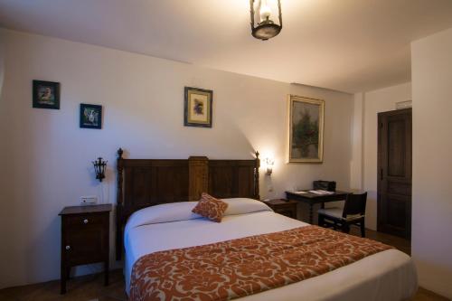 a hotel room with a bed and a desk and a table at Posada y Apartamentos Trebuesto de Guriezo in Trebuesto